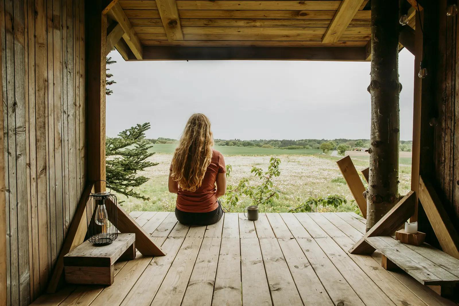 Mujer observando el paisaje desde una ventana, en un momento de reflexión.